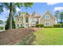 Two-story tan home featuring manicured landscaping, dormer windows and a beautiful entry door at 125 Savannah Estates Dr, Atlanta, GA 30350