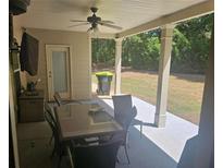 Inviting covered patio with ceiling fan, outdoor seating, and view of the lush backyard at 124 Archstone Sq, Mcdonough, GA 30253