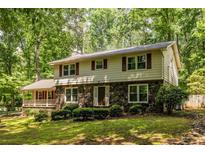 Charming two-story home with stone accents, surrounded by lush trees and a well-manicured lawn at 5410 Rosser Rd, Stone Mountain, GA 30087