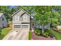 Charming two-story home features a two-car garage, arched entryway, and beautifully landscaped front yard at 1359 Chatley Way, Woodstock, GA 30188