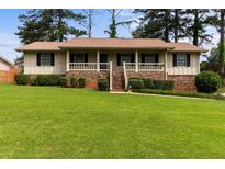 Charming ranch-style home featuring a brick foundation, covered porch, and a well-manicured lawn at 3802 Birchbriar Ct, Decatur, GA 30034