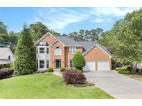 Beautiful brick home with a well-manicured lawn, mature trees, and an attached two car garage at 106 Waterford Place Pl, Acworth, GA 30101