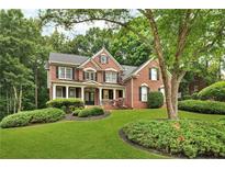 Traditional two-story brick home with well-maintained landscaping and mature shade tree in the front yard at 870 River Cliff Ct, Suwanee, GA 30024