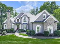 Elegant two-story home with a stone chimney, arched windows, and a beautifully landscaped front yard at 237 Libby Ln, Canton, GA 30115