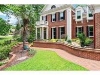 Beautiful brick home with manicured lawn, walkway, a balcony, and black shutters on the windows at 311 Rolling Rock Se Rd, Marietta, GA 30067