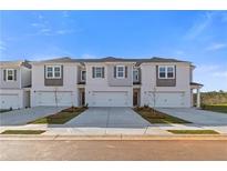 New townhomes featuring symmetrical design, grey shutters, concrete driveway, and manicured landscaping at 321 Heavenly Hollow Pl, Mcdonough, GA 30253