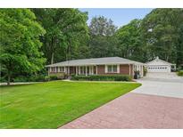 Beautiful red brick home with a lush lawn, mature trees, and a detached two car garage at 2624 Lake Erin Drive Dr, Tucker, GA 30084