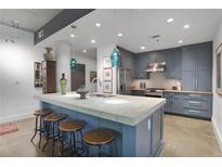 Contemporary kitchen boasts a spacious island, stylish stools, modern lighting, and blue cabinets at 845 Spring Nw St # 129, Atlanta, GA 30308