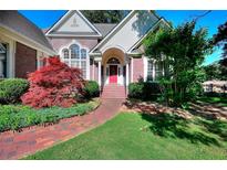 Charming brick home featuring a red front door, lush landscaping, and brick walkway at 1595 Lake Lucerne Rd Sw, Lilburn, GA 30047