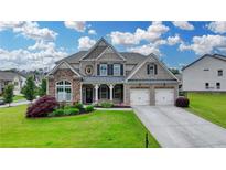Charming two-story home with a well-manicured lawn, beautiful landscaping, and a three car garage at 7470 Oldbury Pl, Cumming, GA 30040