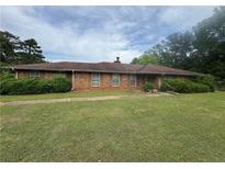Charming one-story brick home featuring a lush green lawn and established landscaping at 1856 Butler Bridge Rd, Covington, GA 30016