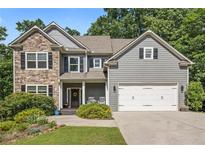 Charming two-story home featuring a stone facade, gray siding, a two-car garage, and manicured landscaping at 27 Rose Brooke Cir, White, GA 30184