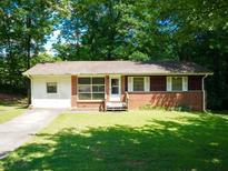 Charming single-story home with a brick facade, a well-maintained lawn, and mature trees creating a serene and inviting atmosphere at 7125 Chappell Cir, Atlanta, GA 30360