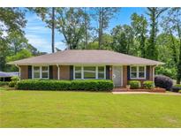 Charming, one-story brick home featuring a well-manicured lawn and lush shrubbery at 2320 Tilson Cir, Decatur, GA 30032