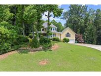 Charming yellow two-story home with a wraparound porch and lush green lawn at 1713 Dudley Dr, Woodstock, GA 30188