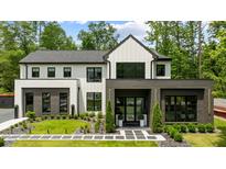 Striking modern home with black trim, white siding, and professionally landscaped front yard at 185 Pebble Trl, Alpharetta, GA 30009