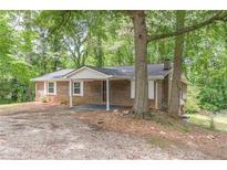 Charming brick home featuring white shutters and a covered front porch nestled among mature trees at 143 Longview Rd, Fayetteville, GA 30214