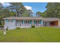 Charming one-story home featuring a covered porch with decorative railings and an attached carport at 4002 Phylis Pl, Decatur, GA 30035