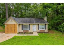 Charming one-story house with black shutters and a well-maintained lawn surrounded by lush greenery at 5856 Rock Rd, Union City, GA 30291