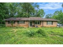 Ranch-style home featuring a brick exterior, surrounded by trees, and a spacious front yard at 2087 Chestnut Way, Lithia Springs, GA 30122