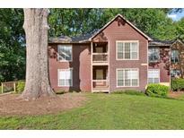 Inviting two-story home with a brown exterior, balcony, and a well-maintained lawn with mature trees at 5555 Mountain Springs Cir, Stone Mountain, GA 30088