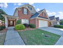 Charming two-story brick home featuring a well-manicured lawn and attached two-car garage at 1885 Hickory Station Cir, Snellville, GA 30078