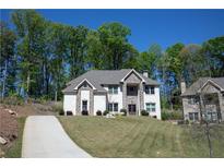Charming two-story home features a brick and stone facade, complemented by mature trees and a well-manicured lawn at 5663 Eternal Dr, Atlanta, GA 30349