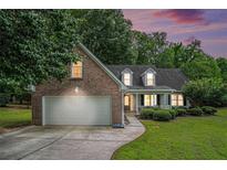 Charming brick home with two car garage and a well maintained front yard at dusk at 609 Ashton Manor Dr, Loganville, GA 30052