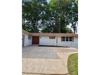 Charming single-story home with a spacious driveway and white painted brick, complemented by lush trees at 4376 Riverwood Cir, Decatur, GA 30035