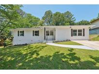 Charming exterior of home with manicured lawn, featuring a brick facade, dark shutters, and a concrete walkway at 2105 Royal Fox Way, Decatur, GA 30032