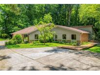Ranch home featuring horizontal siding, brick accents, a large yard and mature trees at 1690 Trotters Ln, Stone Mountain, GA 30087