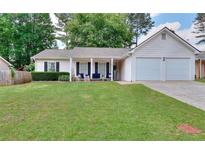 Charming single-story home with a well-manicured lawn, inviting porch, and a two car garage at 2465 Planters Cove Cir, Lawrenceville, GA 30044