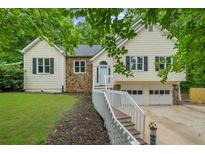 Charming home with stone accents, light siding, and a well-maintained front yard with trees at 5640 Rolling Oaks Dr, Cumming, GA 30040