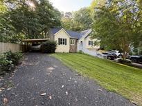 Charming two-story home with landscaped yard, a carport, and ample parking space on a sunny day at 5640 Rolling Oaks Dr, Cumming, GA 30040