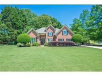 Charming red brick home featuring a well-manicured lawn and lush landscaping, perfect for curb appeal at 7045 Grand View Way, Suwanee, GA 30024