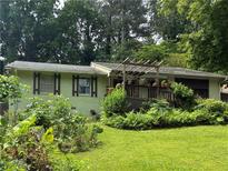 Charming ranch-style home with a wooden pergola-covered porch, lush landscaping, and a vibrant green lawn at 3291 Shady Oak Dr, Atlanta, GA 30340