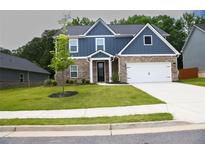 Charming two-story home featuring blue siding, brick accents, a well-manicured lawn, and an attached two-car garage at 3855 Saddle Bag Ct, Dacula, GA 30019