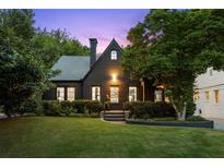 Charming two-story home with dark exterior, manicured lawn, and mature trees at 570 Martina Ne Dr, Atlanta, GA 30305