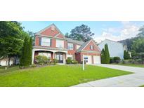 Charming two-story brick home with a manicured lawn and well-maintained landscaping at 779 Avonley Creek Trce, Sugar Hill, GA 30518