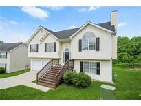 Charming two-story home featuring a black roof, light siding, and a welcoming staircase leading to the front door at 11072 Pebble Ridge Dr, Hampton, GA 30228