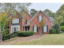 Charming two-story brick home with well-manicured landscaping, shutters, and an American flag at 3565 Hickory Branch Trl, Suwanee, GA 30024