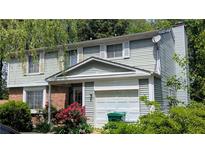 Two-story home with light-green vinyl siding, brick accents, white trim, and a one-car garage at 4256 Village Square Ln, Stone Mountain, GA 30083