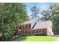 Charming two-story brick home with black shutters, manicured lawn, and mature trees adding curb appeal at 3837 Fenway Xing, Marietta, GA 30062