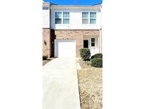 Two-story townhome with white siding, brick accents, an attached garage, and well-maintained landscaping at 6408 Kennonbriar Ct, Lithonia, GA 30058