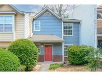 Charming townhome featuring a red door, light blue siding, brick accents, and well-maintained landscaping at 3263 Long Iron Pl, Lawrenceville, GA 30044