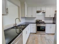Modern kitchen featuring white cabinets, stainless steel appliances, and sleek black countertops at 3263 Long Iron Pl, Lawrenceville, GA 30044