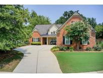 Charming two-story brick home with a well-manicured lawn and a long driveway at 5220 Wild Cedar Dr, Buford, GA 30518