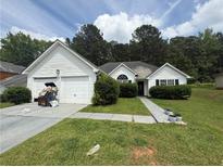 Charming single-story home with white siding, green lawn, and a two-car garage and mature trees at 160 Goldleaf Dr, Hampton, GA 30228