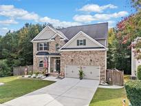 Charming two-story brick home with a well-manicured lawn, two-car garage and beautiful landscaping at 3865 Brookhollow Dr, Douglasville, GA 30135