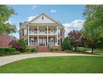 Beautiful two-story brick home featuring a double porch, manicured lawn and mature trees at 230 Summerhouse Ln, Atlanta, GA 30350